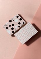 Stylish business cards with polka dot and geometric patterns on soft pink background for modern branding and corporate identity.