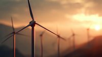 Wind turbines silhouetted against dramatic sunset sky, generating renewable energy in mountainous landscape. Clean power production for sustainable future.