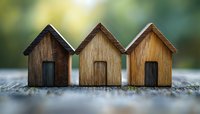 Three miniature wooden houses in a row on rustic surface with soft bokeh background, representing real estate, neighborhood community and home ownership concept.