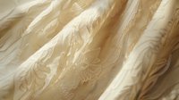 Delicate ivory lace fabric with floral embroidery pattern creates soft folds and textures, capturing light and shadow in elegant wedding dress material.