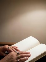 Mature woman with rings on her fingers reading an open blank book with neutral beige background, suitable for education, literature, and publishing concepts.