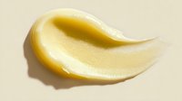 Smooth golden cosmetic cream smear texture on beige background, showing luxurious skincare product consistency for beauty and personal care advertising.