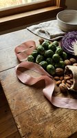 Fresh Brussels sprouts, walnuts and purple cabbage arranged on rustic wooden table with pink ribbon for healthy cooking and seasonal meal preparation.