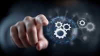 Male hand pointing at digital gear icons with futuristic interface overlay on dark background, representing business automation and technological innovation process.