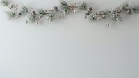 Festive evergreen garland with frosted pinecones and silver ornaments arranged on white background for holiday decorating and seasonal design projects.