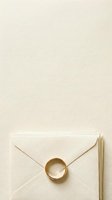 Cream envelope with gold wax seal and dried grass on beige textured background, suitable for wedding invitations, stationery design, and luxury branding projects.
