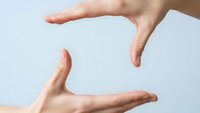 Two hands forming protective frame gesture on white background for safety security and care concepts.
