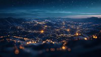 Aerial night cityscape with glowing lights and bokeh effect against mountain backdrop under starry sky, creating dreamy urban atmosphere.