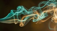 Abstract flowing smoke waves in turquoise and golden colors creating elegant curved patterns on dark background for modern design projects.