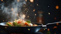 Dramatic cooking scene with stir-fried noodles and vegetables in wok pan against dark background with steam and glowing particles creating magical atmosphere.