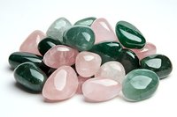 Polished rose quartz and green aventurine healing crystals arranged on white background, showing natural mineral texture and translucent properties for wellness and meditation.