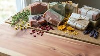 Handmade natural soap bars with dried flowers and herbs on wooden surface for organic skincare and spa treatments.