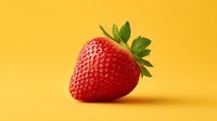 Fresh ripe strawberry with green leaves on bright yellow background for healthy eating and summer fruit concepts.