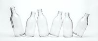 Empty clear glass bottles collection arranged in row on white background isolated for recycling and eco-friendly packaging design concepts.