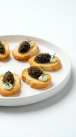 Gourmet caviar canapés with crispy toasted bread rounds topped with creamy spread, luxurious black caviar pearls, and fresh microgreens on white plate for fine dining and upscale events.