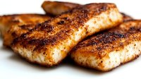 Grilled salmon fillets with crispy blackened seasoning and caramelized crust on white background, close up view showing flaky texture and golden-brown surface.