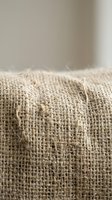 Natural burlap fabric texture close-up with visible weave pattern and loose threads for rustic design projects and eco-friendly packaging concepts.