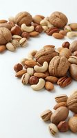 Mixed nuts collection with walnuts, almonds, cashews, pecans and pistachios scattered on white background for healthy snacking and cooking recipes.