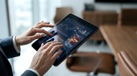 Business professional analyzing financial data charts and graphs on tablet device in modern office workspace for investment decisions.