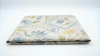 Folded fabric with botanical floral pattern featuring blue and yellow flowers on cream background, suitable for textile design, home decor, and craft projects.