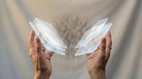 Mature male hands holding translucent holographic leaf shapes against neutral backdrop, representing technology, innovation, sustainability, and digital transformation concepts for business and environmental themes.