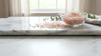 Pink Himalayan salt crystals in glass bowl on marble counter with herbs for natural wellness and cooking seasoning in bright kitchen interior.
