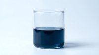 Glass beaker filled with dark blue liquid isolated on white background, suitable for science, chemistry, laboratory, and educational design projects.
