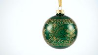 Green Christmas ornament with gold decorative patterns hanging on ribbon against white background for holiday decorations and festive designs.