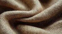 Natural linen fabric with soft waves and folds creating elegant texture and shadows, close-up macro shot showing detailed burlap weave pattern.
