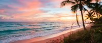 Tropical beach at sunset with palm trees, golden sand, and turquoise waves. Serene coastal landscape for travel, vacation, and relaxation themes.