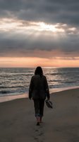 Woman with long dark hair walking barefoot on sandy beach at sunset, carrying shoes, wearing casual jacket. Dramatic cloudy sky with golden sunlight rays breaking through clouds over ocean waves.