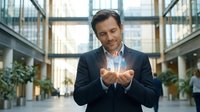 Professional businessman in suit holding glowing holographic data visualization in modern office lobby, representing digital transformation and innovation.