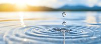 Clear water drops falling creating concentric ripples on calm water surface with soft sunset light and mountains in background, macro photography capturing liquid motion.