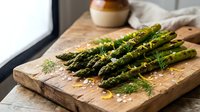 Fresh green asparagus spears with herbs and seasonings on rustic wooden cutting board in modern kitchen setting for healthy cooking and meal preparation.