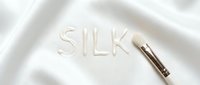 Luxury silk fabric with embossed text and cosmetic brush on white background, suitable for beauty, skincare, and fashion design projects.