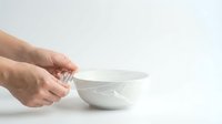 Hand holding empty white ceramic bowl on isolated background, ready for food styling, product mockup, and kitchen design projects.