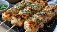 Grilled chicken skewers with herbs and spices on wooden sticks, perfect for barbecue parties, outdoor cooking, and summer dining experiences.