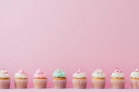 Row of colorful cupcakes with frosting and sprinkles arranged in line against pastel pink background, perfect for bakery marketing.
