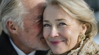 Loving senior couple sharing intimate moment, mature man kissing woman's cheek, expressing affection and romance in golden years of marriage and partnership.