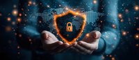 Hands holding glowing shield with padlock icon, orange light particles and world map background representing cybersecurity and digital data protection concept.