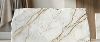 Elegant white marble slab with golden veining displayed in modern interior showroom for luxury kitchen countertops and bathroom design applications.