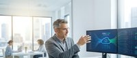 Mature businessman with gray hair analyzing cloud computing data on multiple monitors in modern office environment for technology presentations.