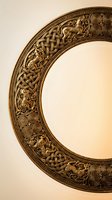 Ornate bronze circular frame with intricate Celtic knotwork patterns and spiral motifs on neutral background for decorative design projects.