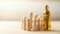 Golden leader figure standing apart from group of wooden people on neutral background representing leadership, management and business hierarchy concepts.