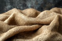 Natural burlap fabric with waves and folds creating soft shadows and texture, macro shot showing detailed woven jute fibers in warm brown tones.