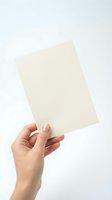 Female hand holding blank cream colored paper sheets against white background isolated for mockup design and presentation templates.
