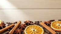 Aromatic winter spices with dried orange slices, cinnamon sticks, star anise and cloves arranged on wooden background for seasonal cooking and baking.