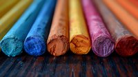 Colorful artistic chalk pastels arranged in row showing vibrant pigments and texture, perfect for education, art and creativity concepts on dark wooden background.