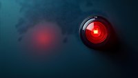 Glowing red surveillance camera lens on dark background with red light reflection, representing security monitoring and digital surveillance technology.