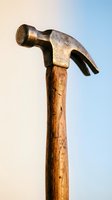 Vintage claw hammer with weathered wooden handle against gradient sky background for construction and carpentry projects.